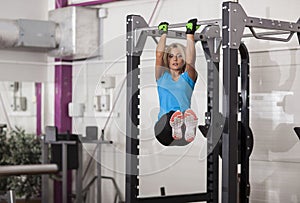 Bodybuilding. Strong fit woman exercising in a gym - doing pull-ups.