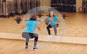 Bodybuilding. woman exercising with barbell in fitness class. Female workout in gym doing squats with weight