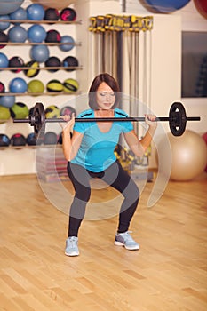 Bodybuilding. woman exercising with barbell in fitness class. Female workout in gym doing squats with weight.