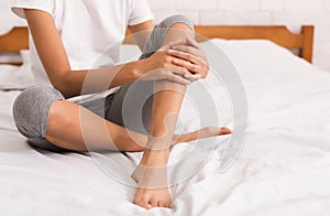 Bodycare. Woman with bare legs sitting on bed