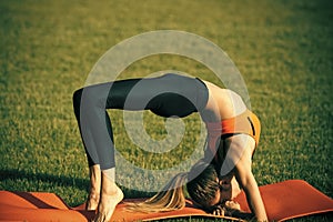 Bodycare woman in crab position on green grass, body care