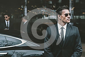 bodyguard standing at businessman car and reviewing photo