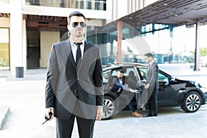 Bodyguard Staying Alert While Colleague Opening Car Door For VIP