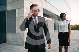 Bodyguard in sunglasses and black business woman