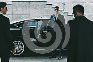 bodyguard in sunglasses opening car door