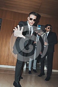 bodyguard in sunglasses stopping paparazzi when celebrity going out from