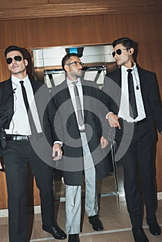 bodyguards and businessman walking from elevator