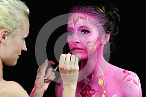 Bodypaint master in work, paints a model for a photo shoot