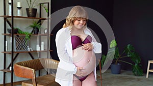 Bodypositive. pregnant woman with overweight in underwear stroking belly.