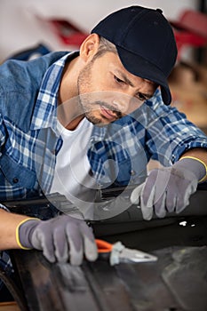 bodyworker repairs panel using pliers
