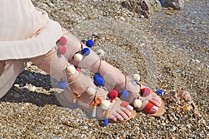 Bohemian greek sandals with colorful pom pom advertisement on the beach