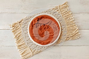 Bohemian rustic newborn background - white bowl with macrame and dry wheat on white wooden floor
