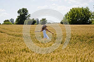 Bohemian style of clothing. girl dancing in a field in a beautiful white dress at sunset. beautiful carefree woman has windy hair