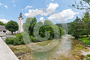 Bohinj church, Slovenia - view of river in the Ribcev Laz village. Tourist on the kayak and canoe on the river. Hiking in the Slov