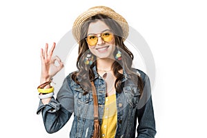 Boho girl in boater and sunglasses showing okay sign isolated on white