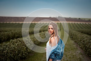 Boho hippie girl with jeans jacket and white dress in field