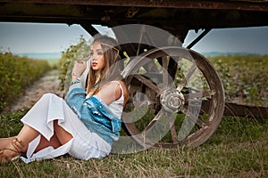 Boho hippie girl with jeans jacket and white dress near trailer