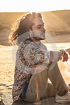 Boho hippie man meditating on the sandy desert