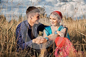 Boho style attractive couple in love posing on the autumn field.