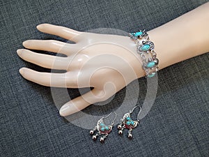 Boho style ethnic silver bracelet and earrings with turquose stones on mannequin hand