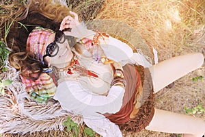 Boho style happy smiling girl portrait lying on a hay and fur