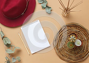 Boho style modern minimal home workspace desk with notebook, succulent, hat, aroma sticks, napkins on beige background.