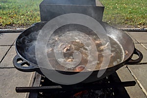 Boil the broth with meat and vegetables in a cauldron. Cooking shurpa soup over an open fire.