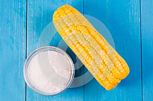 Boiled appetizing corn and salt on a blue wooden background, top view. Healthy food