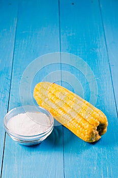 Boiled appetizing corn and salt on a blue wooden background, vegetarian concept. Copy space. Healthy food