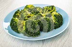 Boiled broccoli in blue plate on wooden plate