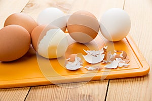 Boiled brown and white eggs, eggshell on chopping board