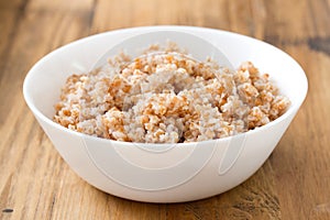 Boiled cereals in white bowl on brown background