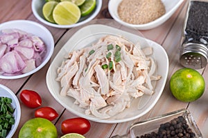 Boiled chicken cut into pieces in a white dish on a wooden table