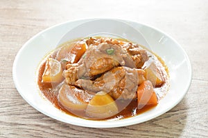 Boiled chicken leg with potato in swet red gravy sauce stew on plate