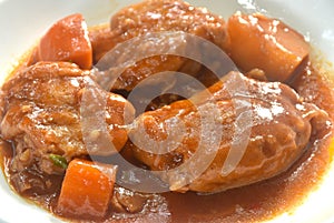 boiled chicken tight with carrot in swet red gravy sauce stew on plate photo