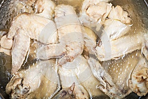 Boiled chicken wings in greasy bouillon in stewpan