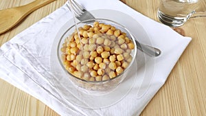 Boiled chickpeas are poured with vegetable oil. Ready peas in glass bowl. Protein-rich bean. Cooking healthy vegan food. Closeup,