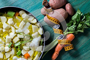 Boiled cod with potatoes, celery and carrots. Close-up of pan ready to cook, on green wooden background