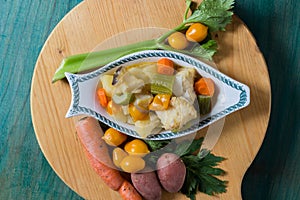 Boiled cod with potatoes, celery and carrots. Close-up of plate ready to cook, on green wooden background