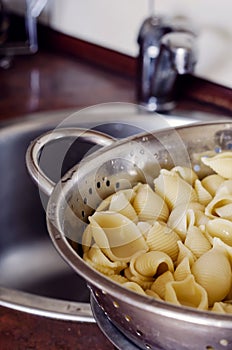 Boiled Conchiglie in a metal colander