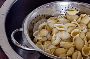 Boiled Conchiglie in a metal colander