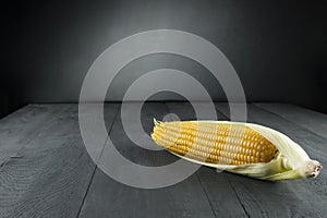 Boiled corn with leaf on black backdrop and background