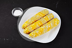 boiled corn on a white square plate, dark table, hodgepodge photo
