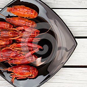 Boiled crawfish. Woden background. Rustic style. Red boiled crawfish on the black rectangular plate.