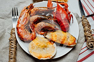 Boiled crayfish, baked scallops and mussels, fried langoustines and shrimps on a white plate