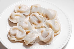 Boiled dumplings are arranged in a circle on a white plate.
