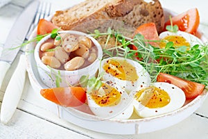 Boiled egg, beans, toast and green herbs