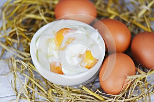 Boiled egg on bowl and fresh eggs on straw background - Soft boiled eggs