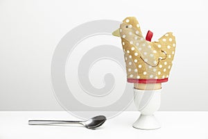 Boiled egg in cup with hen egg warmer and spoon