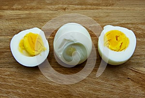 Boiled egg with a cut boiled egg on wooden table